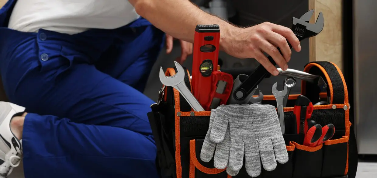 Person reaching for wrench in tool bag.