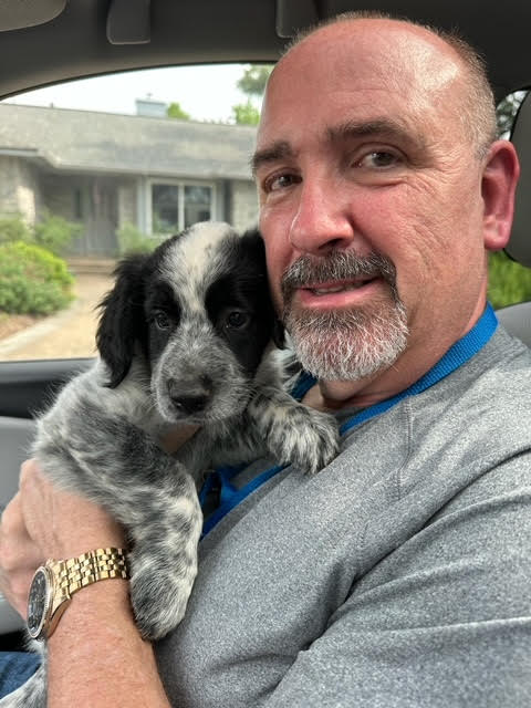 Image20250505102401 A man holding a puppy in his arms.